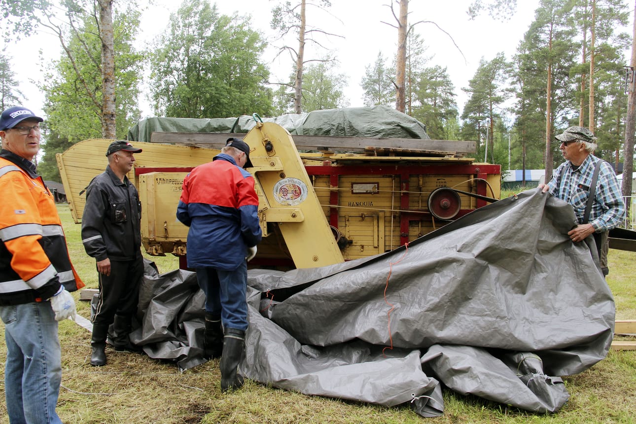 Puintinäytöksen koneet ovat valmiina. Aarne Koutonen, Matti Ahola, Markku Taka-Eilola ja Seppo Sallmén peittelevät koneet sateelta suojaan.