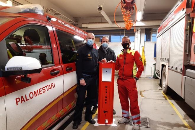 Veslatec Oy lahjoitti valmistamansa käsidesiautomaatin Pohjanmaan pelastuslaitokselle, Vaasan paloasemalle. Jukka Ura, Tom Bergström ja André Åkerholm ihastelevat paloaseman väreihin sopivaa käsidesiautomaattia. Kuva: Enni Yli-Hynnilä