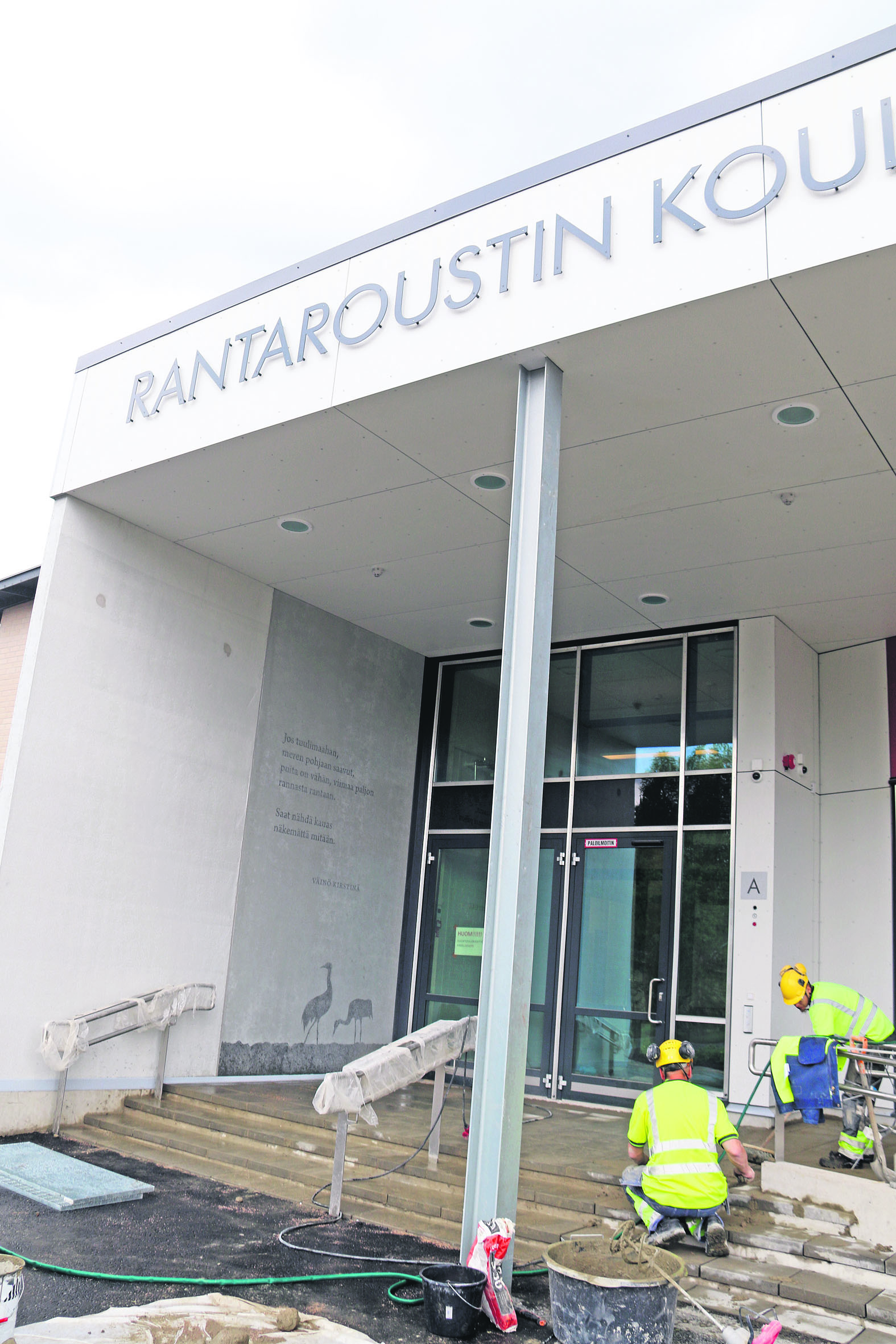 Koulun pääsisäänkäynti. Vasemmalla Väinö Kirstinän runo seinään ikuistettuna.
