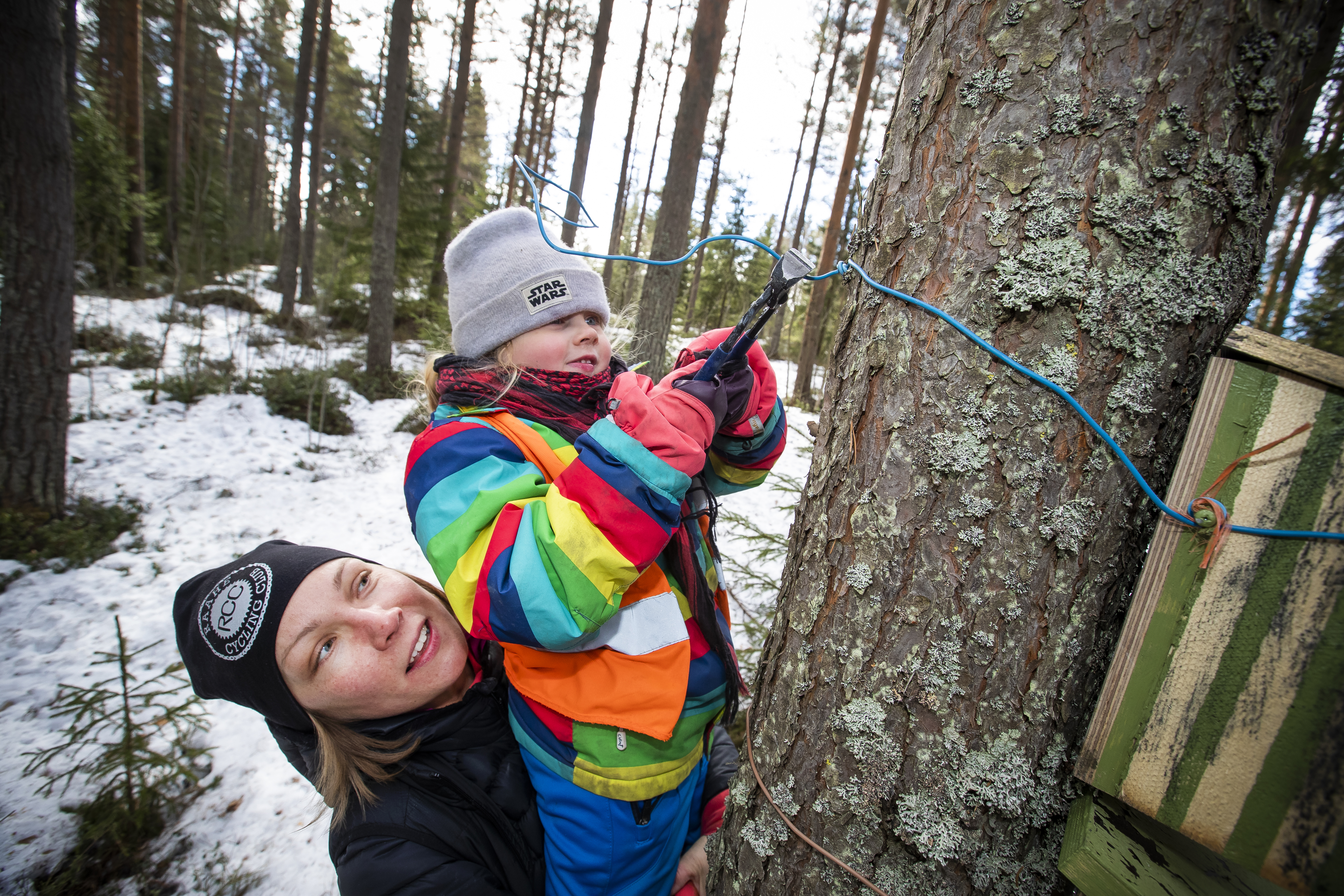 Elina Sivula auttaa Minea Järvelää pöntön ripustamisessa.