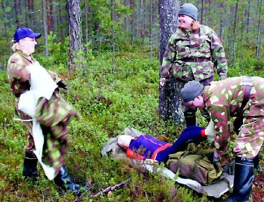 Enni Sarajärvi (kesk.) komensi kuntoutuskoordinaattori Anne Aderssonia (vas.) luovuttamaan takkinsa loukkaantuneen peitteeksi. Esko Mattila pisti reppunsa kohottamaan jalkoja.