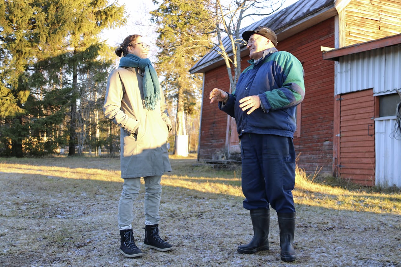 Tapio Moilanen tarinoi Heikki Kurtin talon edustalla. Kurtin talo on jäänyt asumattomaksi aivan kuten Varjakansaarikin. Alueelle toivotaan uutta elinvoimaa yhteisöä herättelemällä ja tarinoita keräämällä. Kuuntelemassa Tanja Råman.