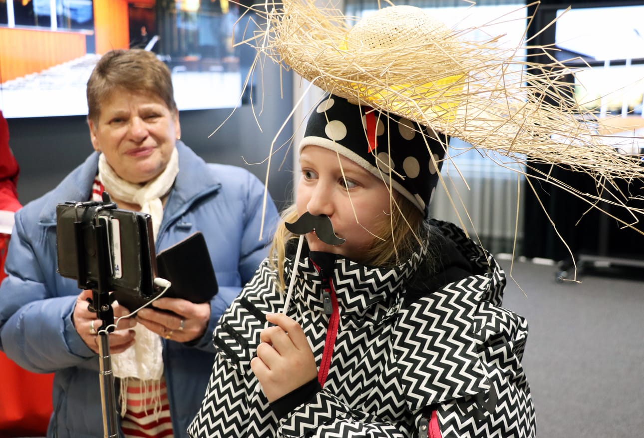 Viivi Vähä ottamassa selfietä paikalle tuodun kuvausrekvisiitan innostamana. Raili Säkkistä naurattaa taustalla.