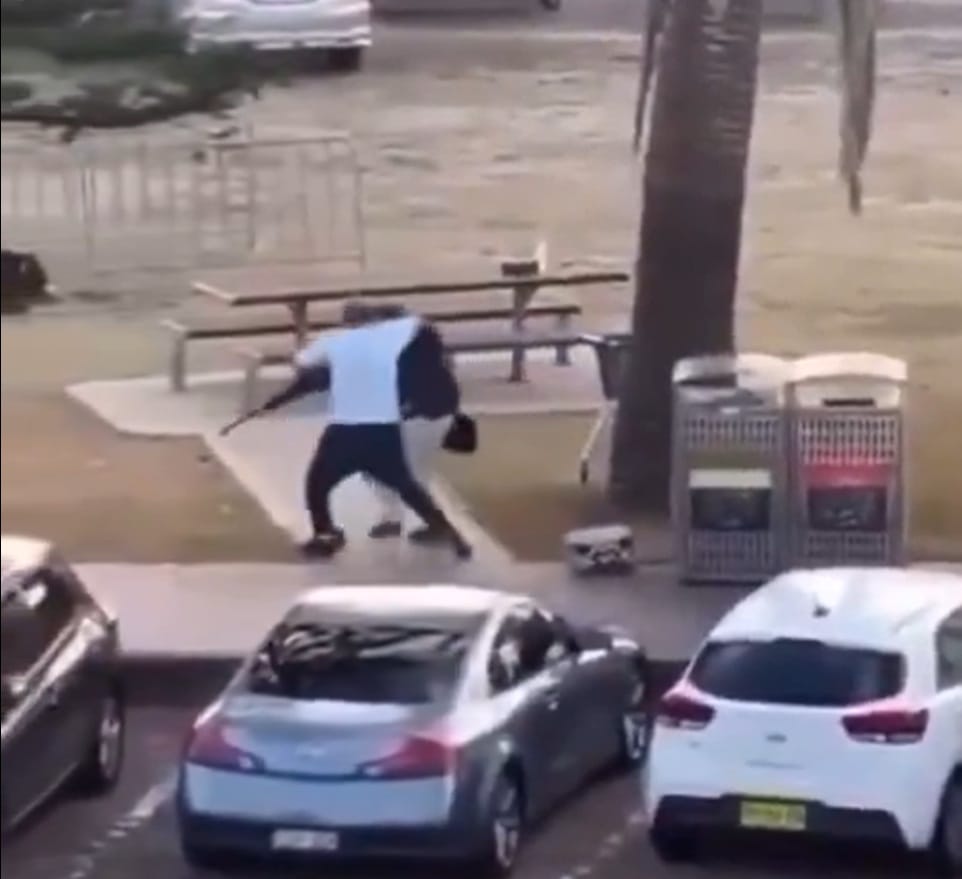 Sivullinen valkopaitainen mies kävi yhden ampujan kimppuun ja onnistui riistämään tältä aseen Sydneyn Bondi Beachilla. Kuvakaappaus sosiaalisessa mediassa levitetystä videosta.