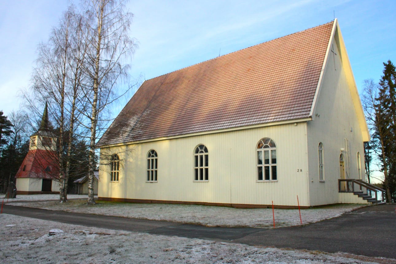 Posion kirkon pihapiiri 10.11.2025. Vasemmalla kellotapuli ja sen vieressä siunauskappeli. Nurmikolla on Evakkokivi, evakossa kuolleiden posiolaisten muistomerkki.