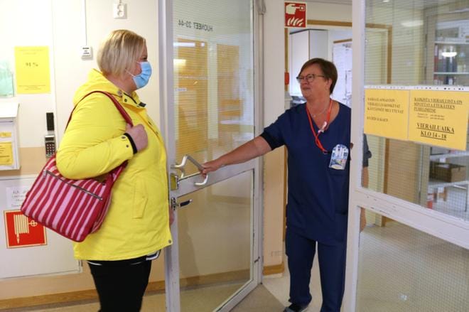 Lavastetussa tilanteessa osastonhoitaja Outi Suominen näytti, millä tavoin varustautuneena osastolle voi mennä käymään. Sairaanhoitaja Salme Annala päästi kollegansa ovesta. KUVA: ANU NAHKALA