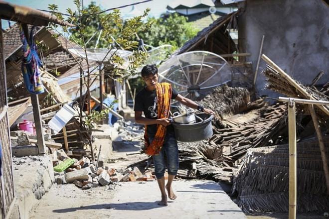 Indonesialainen mies keräsi tavaroitaan romahtaneesta talostaan maanantaina Lombokin saaren pohjoisosissa. KUVA: STR / EPA
