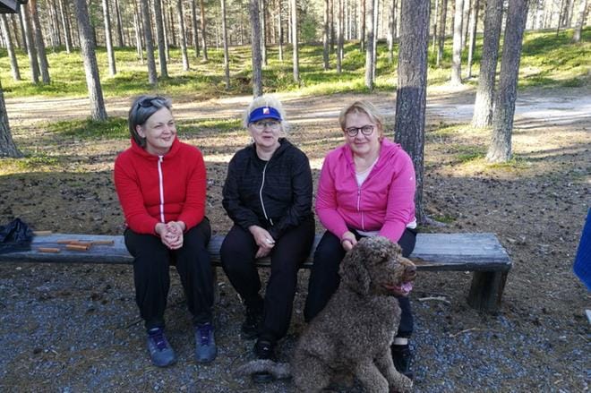 Tyytyväiset ja liikunnalliset patikoitsijat istahtivat lenkin jälkeen nauttimaan kesäillan kauneudesta. Velja-koira myös osallistui patikkaan. Kuvassa (vas.): Anne Timo, Kaija Sivula, Merja Mäkitalo ja Velja-koira. Kuva: Kirsti Kivelä.