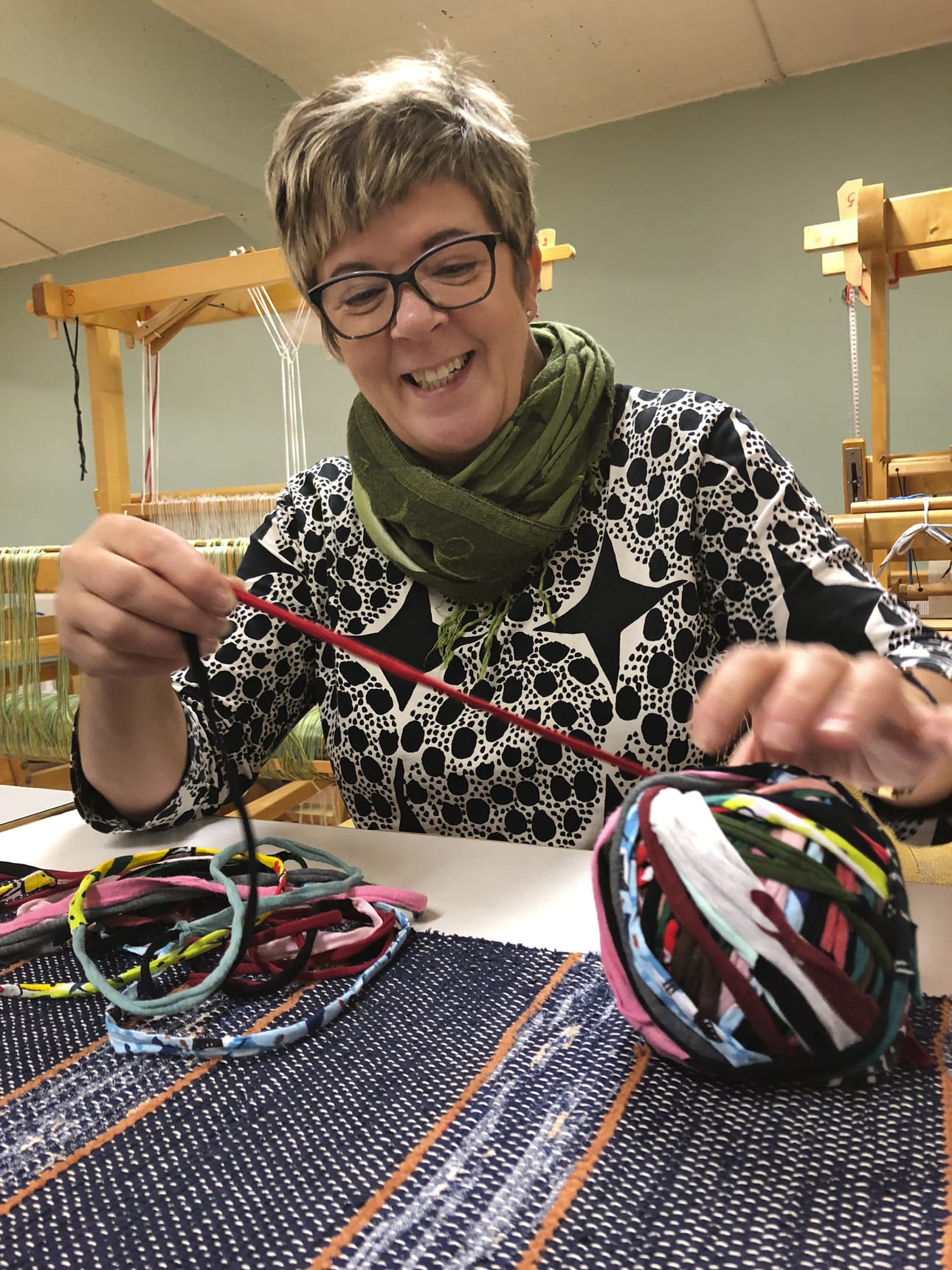 Päivi Körkkö liimaa yhteen trikookuteen pätkiä ja saa niistä värikästä kudetta.