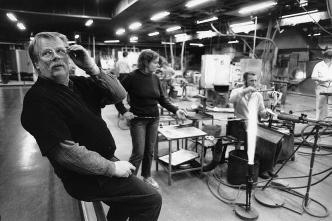 Professori Oiva Toikka (1931–2019) oli Nuutajärven lasitehtaalla suunnittelijana 1960-luvulta lähtien. Hän suunnitteli töitään lasihytissä yhdessä puhaltajien kanssa, ei työpöydän ääressä. Kuva on vuodelta 1987.