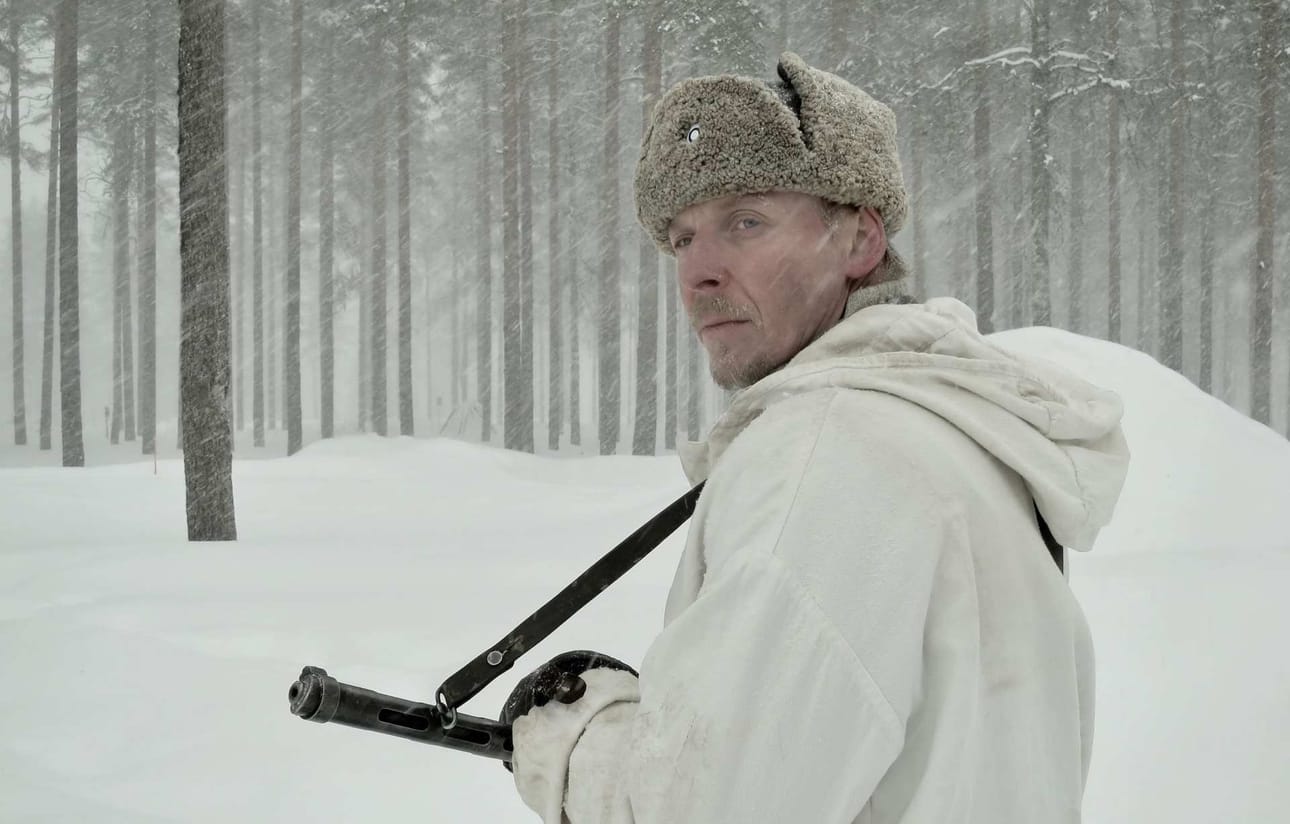 Eero Ahon esittämä Rokka poseeraa uudessa Tuntemattomassa Suomi-konepistoolinsa kanssa jouluisessa maisemassa ennen myyttiseen väijytyskohtaukseen hiihtämistään.