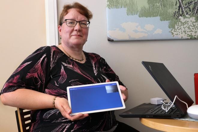 Ritva Ala-Mattinen esittelee asiakkaiden päätelaitetta. Teknistä osaamista sen käyttämiseen ei tarvita, sillä yhteys avautuu automaattisesti, kun hoitaja tai omainen soittaa laitteeseen. KUVA: VILJA VAINIO