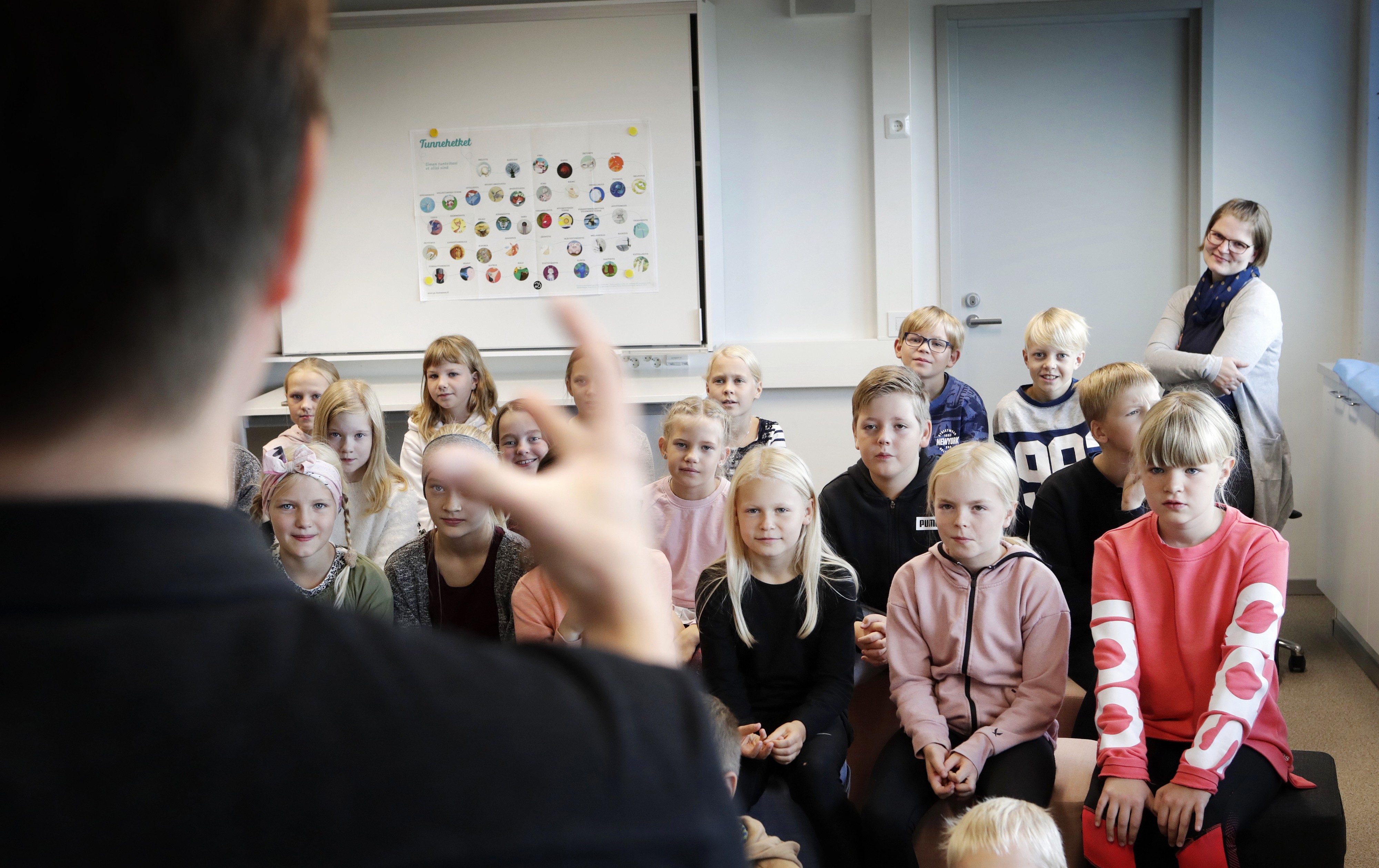 Ojanperän koulun neljäsluokkalaiset kuuntelivat kiinnostuneina kirjailijavieraan kertomusta, miten kirja syntyy. Taustalla opettaja, vararehtori ja kirjastovastaava Suvi Seppälä.