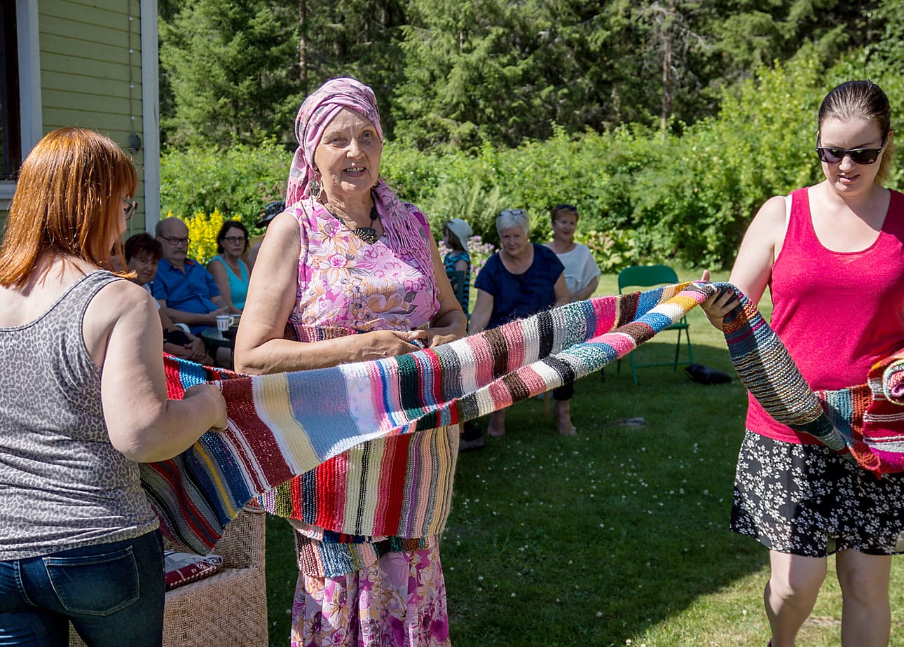 Raakel Pistemaa ja Inka Loikola kietoivat kyläjätin huivia Leila Kastellin ympärille sunnuntaina. Kyläjätti nimettiin Leila Kastellin romaanin julkaisutilaisuudessa Lasikankaalla.