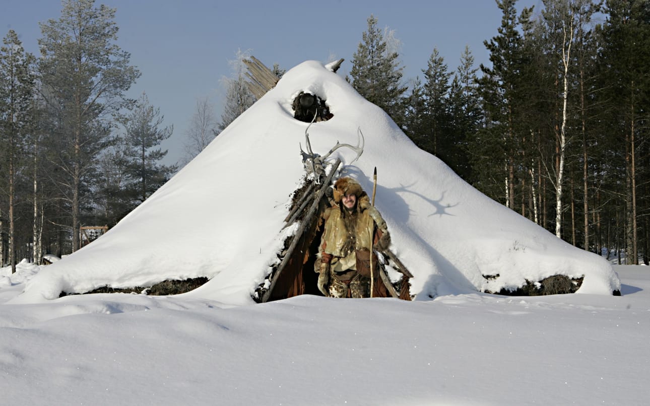 Kierikin kivikautinen kylä ei ole myyntilistalla. Kivikautisen rivitalon edustalla seisova opas ja arkeologi Sami Viljanmaa on pukeutunut jäämies Ötziä mukaillen. Arkistokuva.