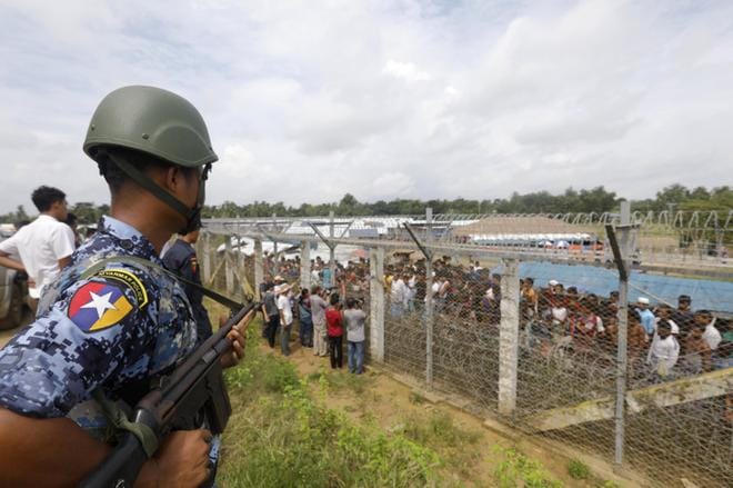 Tuhansia rohingyapakolaisia asuu Myanmarin ja Bangladeshin välissä ei kenenkään maalla. Myanmarilainen rajavartija seurasi kokoontumista piikkiaidan takaa. Pakolaiskriisi alkoi vuosi sitten elokuussa. KUVA: NYEIN CHAN NAING/EPA