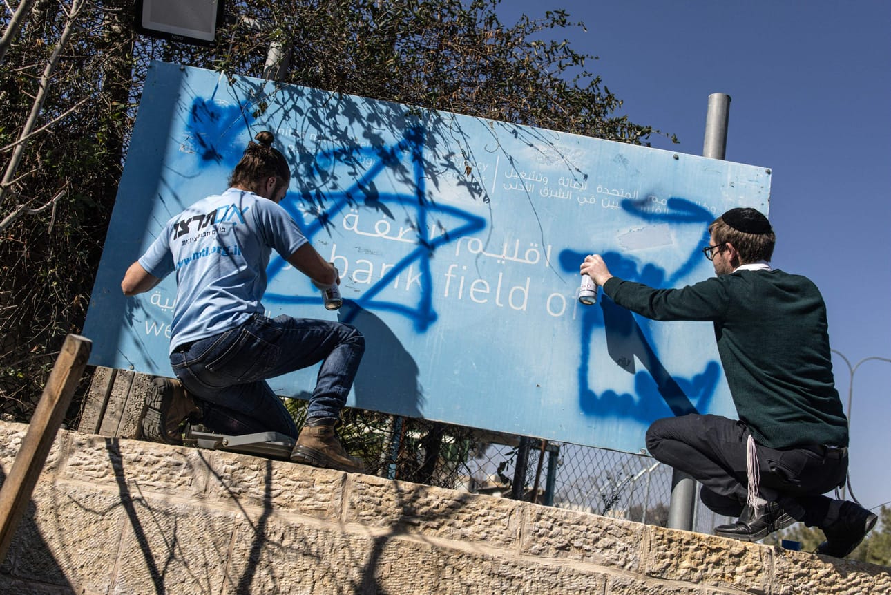 YK:n alaista palestiinalaispakolaisten avustusjärjestöä on torstaina voimaan tulleen lain puitteissa kielletty toimimasta Israelin maaperällä. Kuvassa israelilaiset aktivistit sotkevat järjestön kylttiä. LEHTIKUVA/AFP