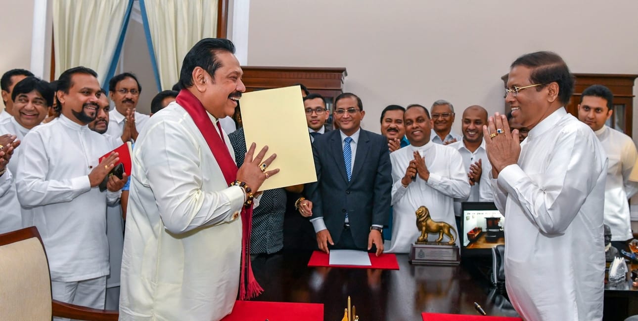 Sri Lankan presidentti Maithripala Sirisena (oik.) ja maan entinen presidentti Mahinda Rajapaksa (vas.) tervehtivät toisiaan Rajapaksan pääministerin virkavalan lausumisen yhteydessä presidentinkansliassa Sri Lankan pääkaupungissa Colombossa 26. lokakuuta 2018.