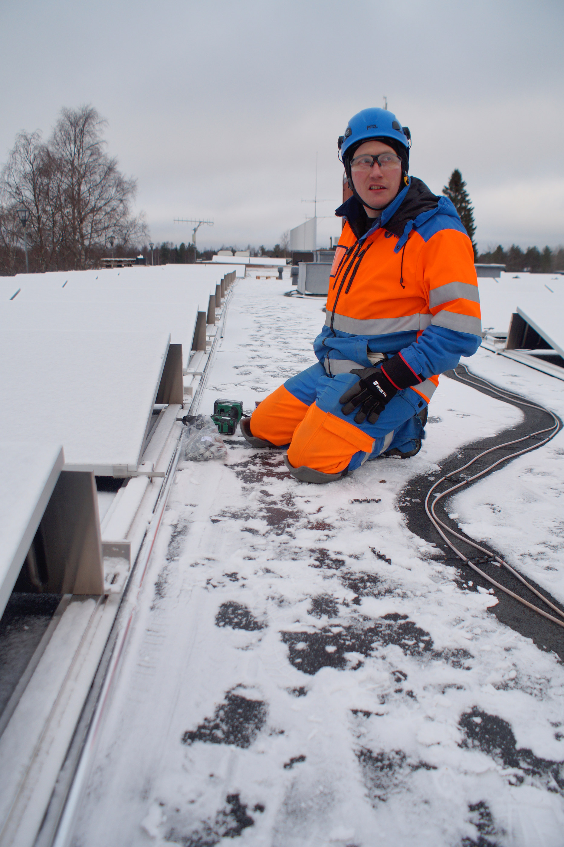 Voimatelin asentaja Juha-Matti Toppinen on ruuvaillut paneelit ja sähköjohdot kohdilleen kaupungintalon katolla olevaan aurinkovoimalaan.