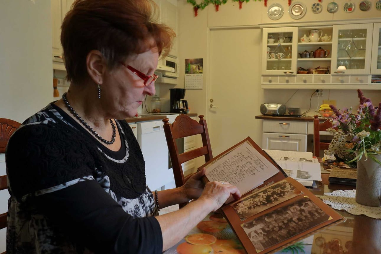Marja Halmetoja tutkii kuvaa vuoden 1920 Palonkylän rippikoululaisista. Valokuvat ovat kyläkirjojen kiinnostavinta antia.