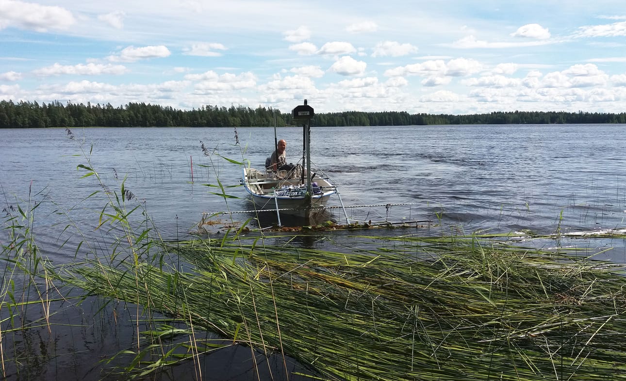 Pekka Karilainen työnsi niitettyä heinää rantaan, josta rannanomistaja nosti ne maalle.