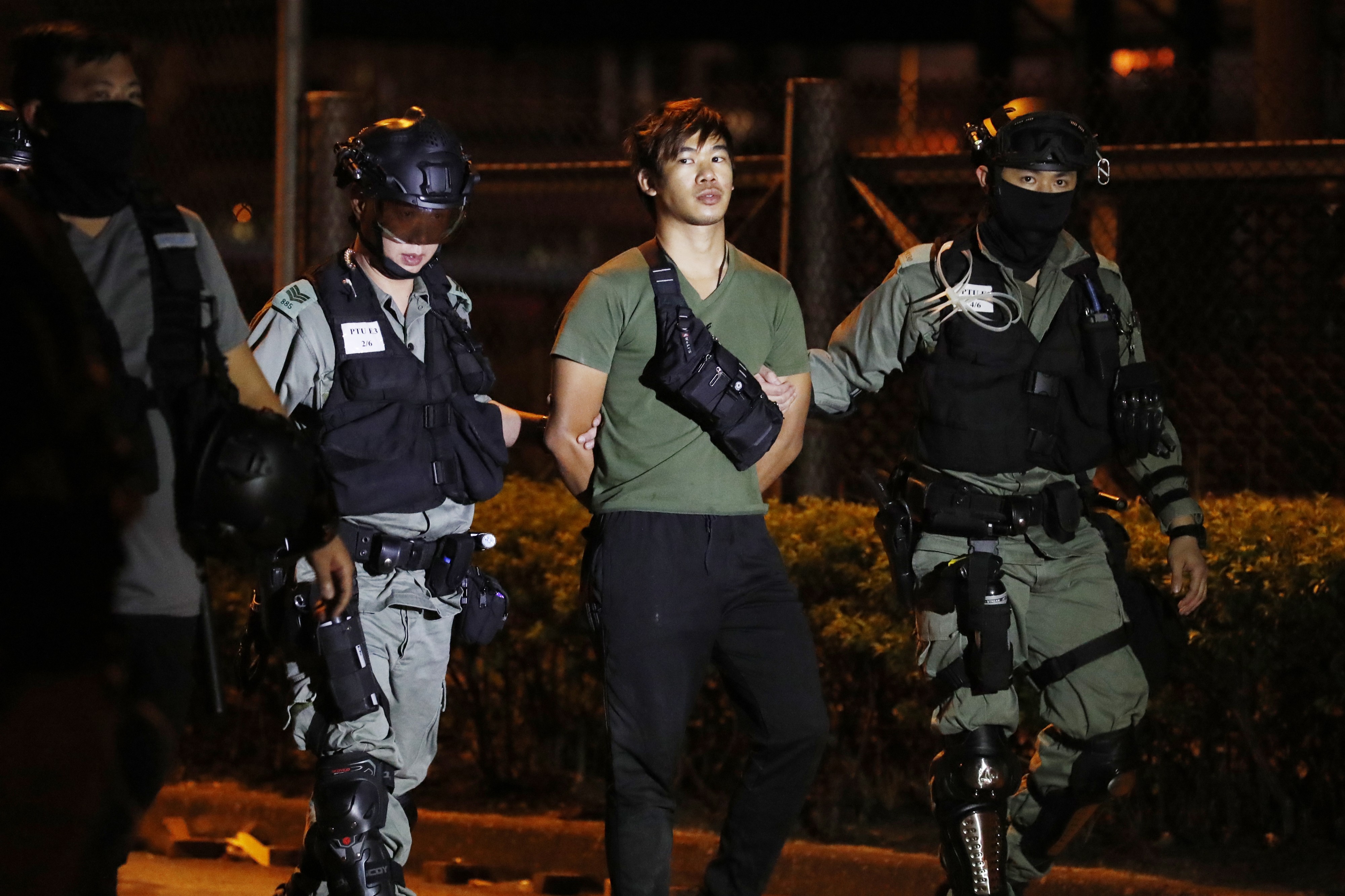 Poliisit taluttivat Hongkongin protesteissa pidättämäänsä miestä tiistaina.
