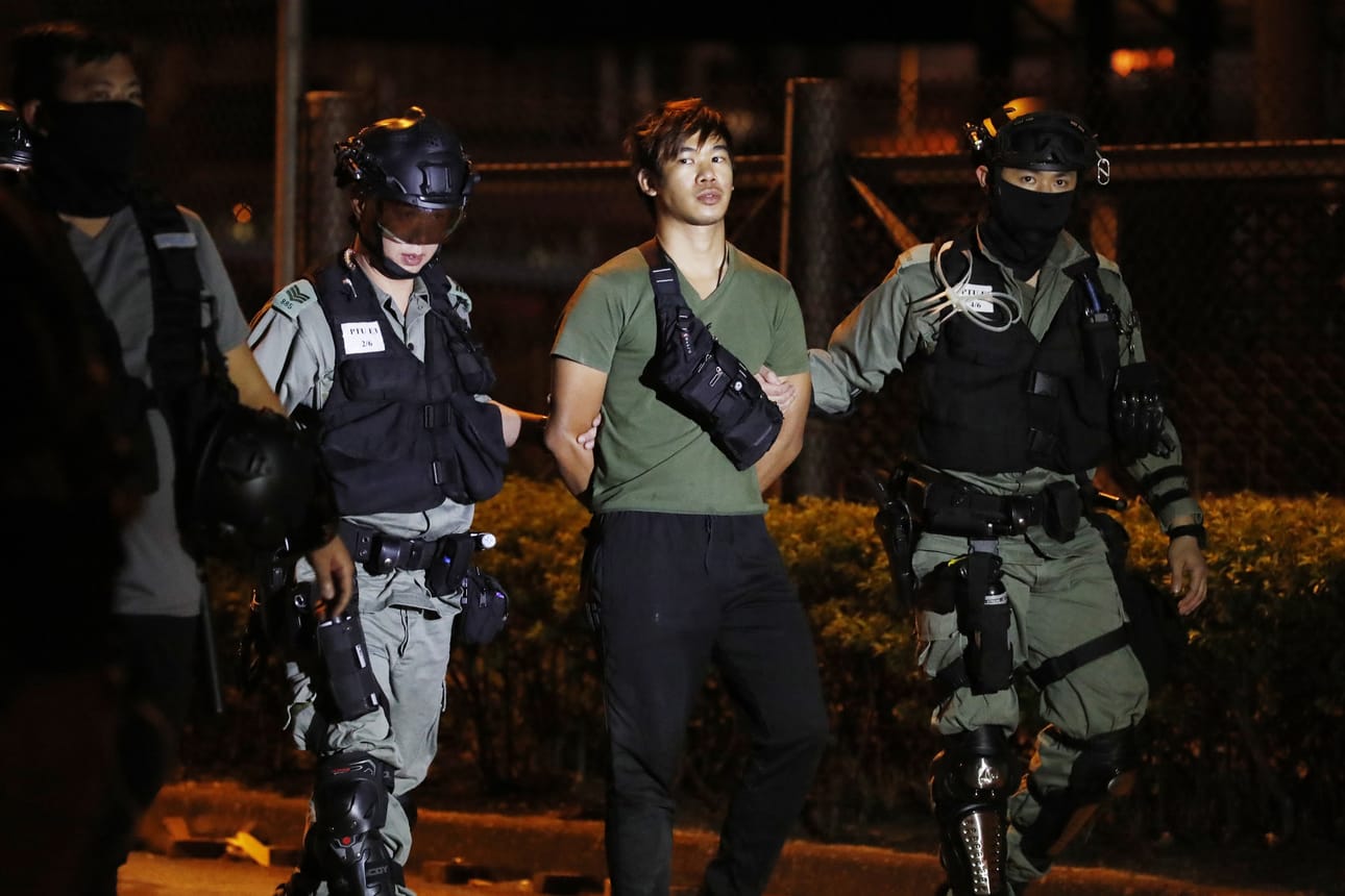 Poliisit taluttivat Hongkongin protesteissa pidättämäänsä miestä tiistaina.