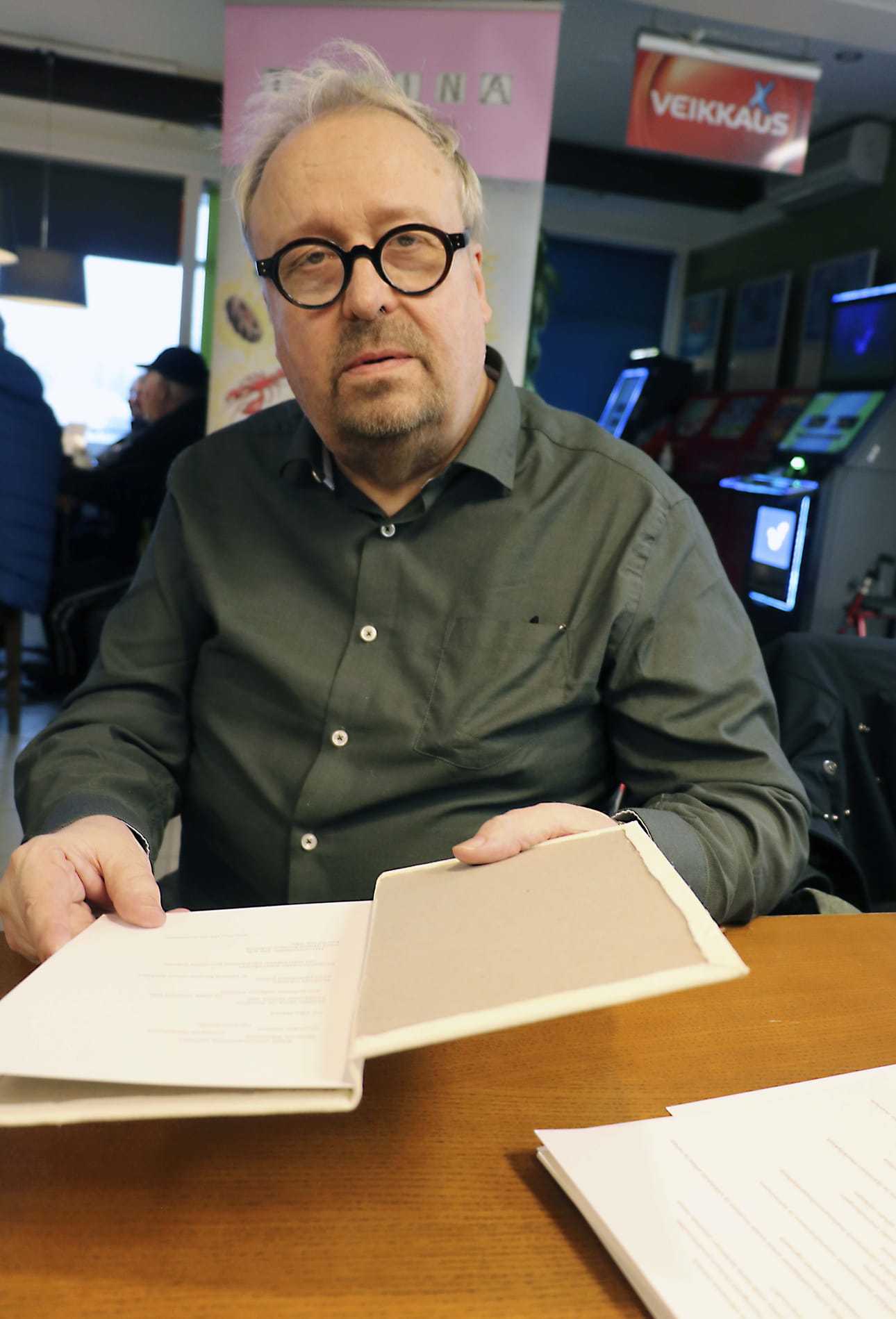 Juha Allan Ekholm tutustui kirja-aihioon, johon huoltoaseman arjesta kertovat tekstit laitetaan. Ekholm on ollut toteuttamassa vuosien aikana useita taide- ja tapahtumaprojekteja Oulaisissa.