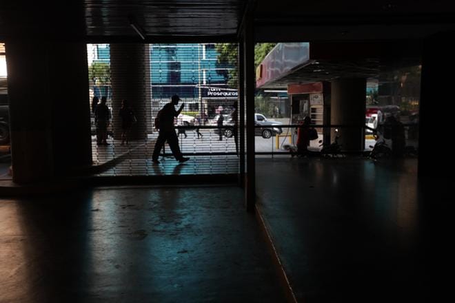 Ryhmä ihmisiä jäi pimeyteen Venezuelan parlamenttirakennuksessa, kun sähkökatko pysäytti taas toimintoja pääkaupungissa Caracasissa. KUVA: RAYNER PENA / EPA