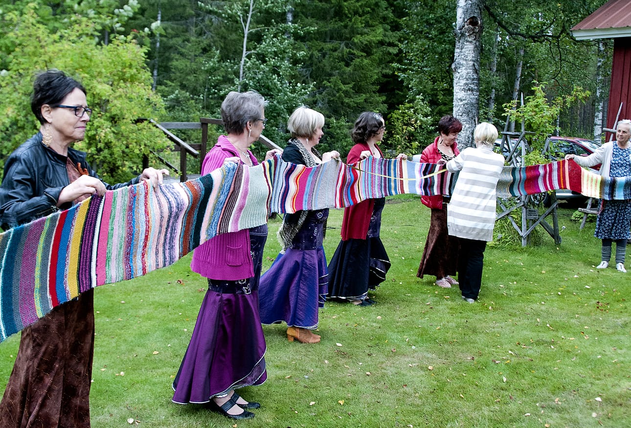Tässä mitataan Ylipään kyläjätin virka-asua, jätinhuivia. Kyläläisten kymmeniä vuosia sitten kutoman huivin mittaa on arvuuteltu, ja nyt se on tiedossa. Huivi on nykyisellä kyläjätillä, Leila Kastellilla (vas.).