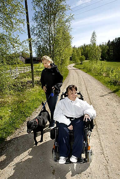 Marjut Korjola pyrkii ajamaan pyörätuolillaan hiljaisia pikkuteitä pitkin. Seuraa matkalla pitävät muun muassa avustaja Milla Honka ja labradorinnoutaja Donna.
