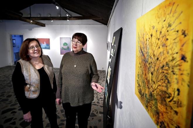 Seinäjoen taidegraafikoiden Seija Saari ja Liisa Malkamo esittelevät Heli Rintamäen Kuuma kesä -vedosta. Taustalla Malkamon paperilaakapainoa, puupiirrosta ja valokuvaa yhdistelevät vedokset. KUVAT: TOMI KOSONEN