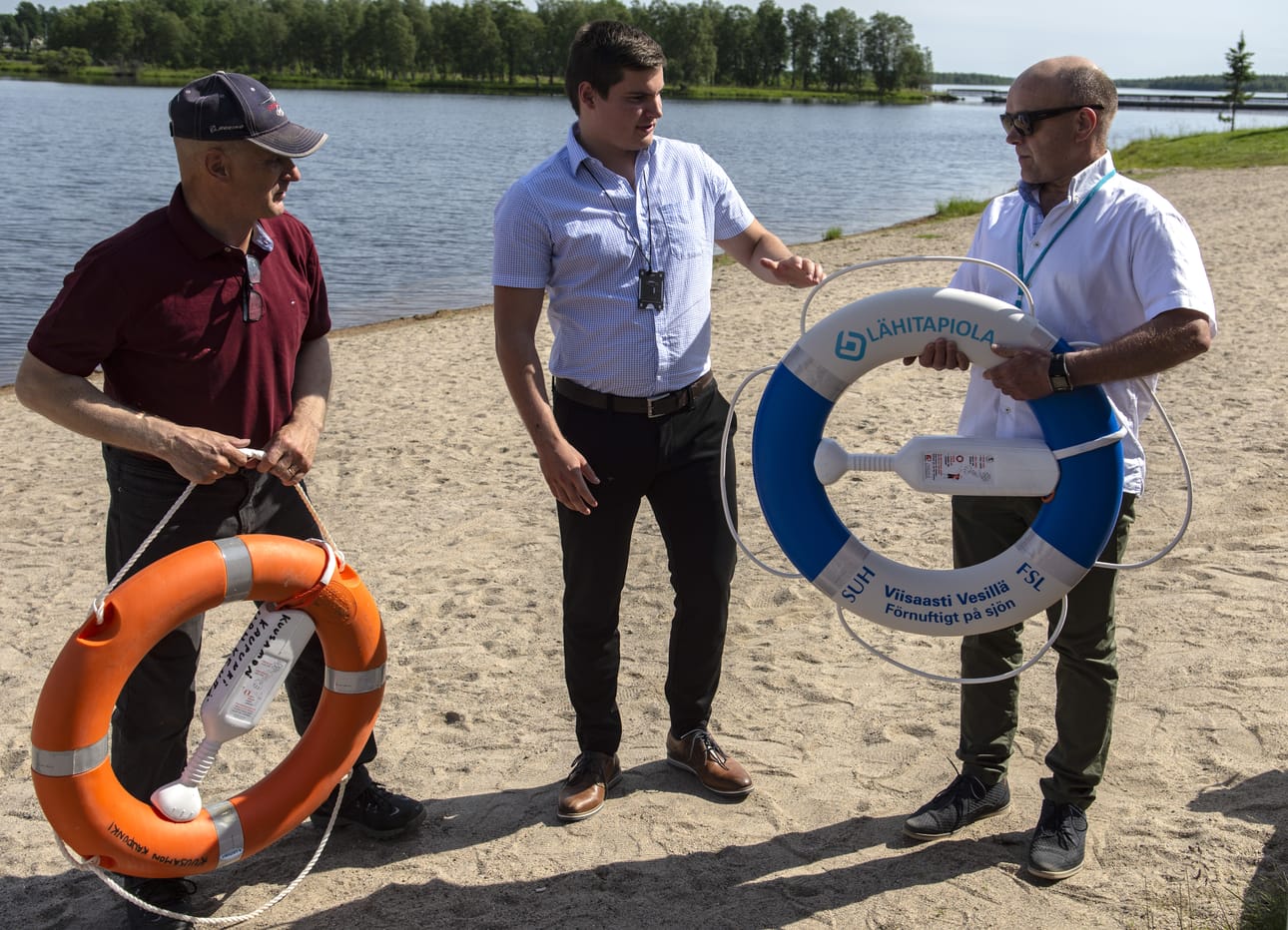 Pelastusrenkaiden vaihto. Vasemmalla kaupungin Viljo Lohilahti, joka on jo poistanut Kelan rannan vanhan pelastusrenkaan paikaltaan. Tilalle tulee vakuutusyhtiön mainostekstiä kantava pelastusrengas. Keskellä Leevi Asikainen ja oikealla Risto Tyni.