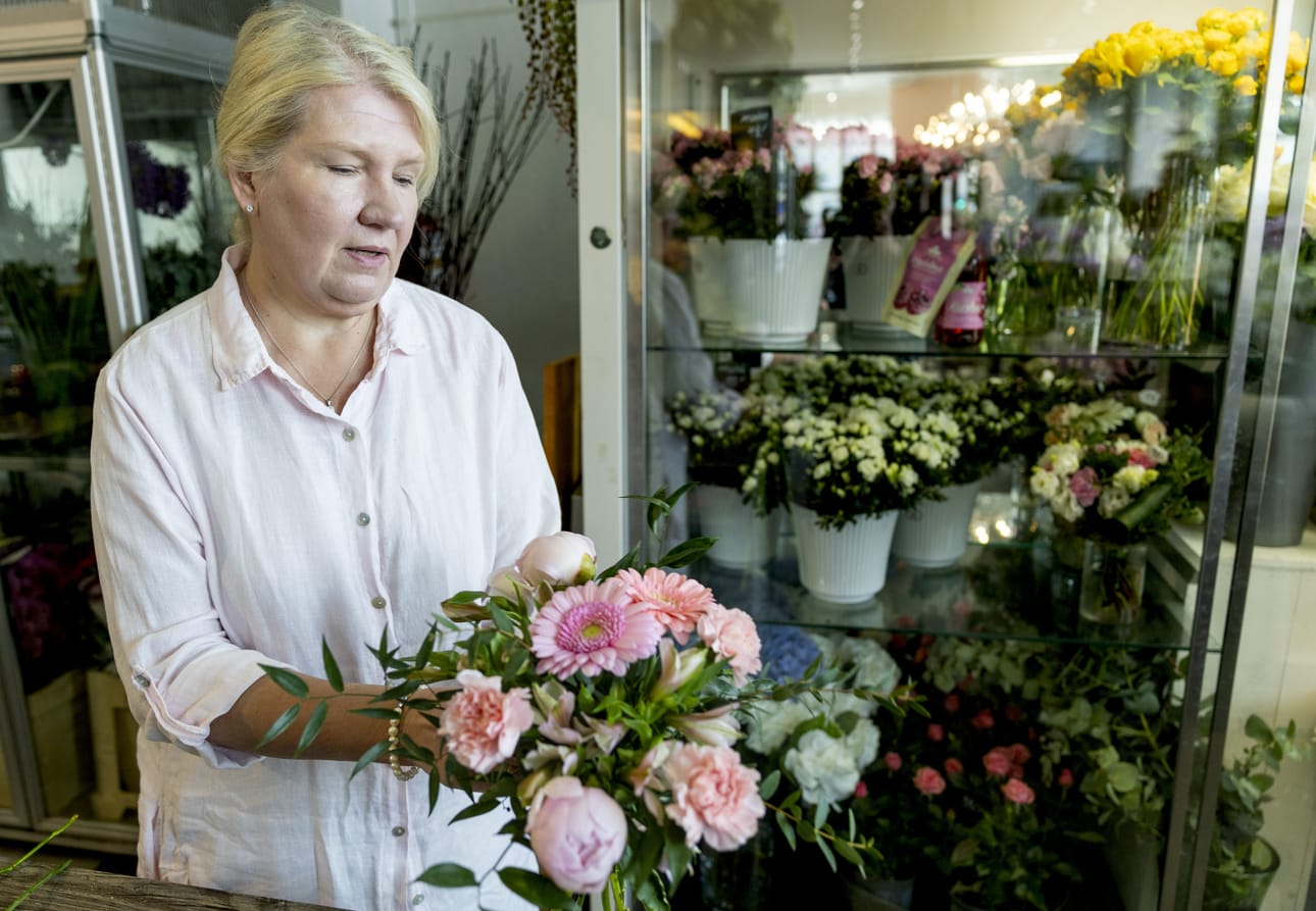 Floristimestari Sari Kuosmanen sitoo leikkokukkakimppua, jossa on muun muassa neilikkaa, pionia, gerberaa ja inkaliljaa.