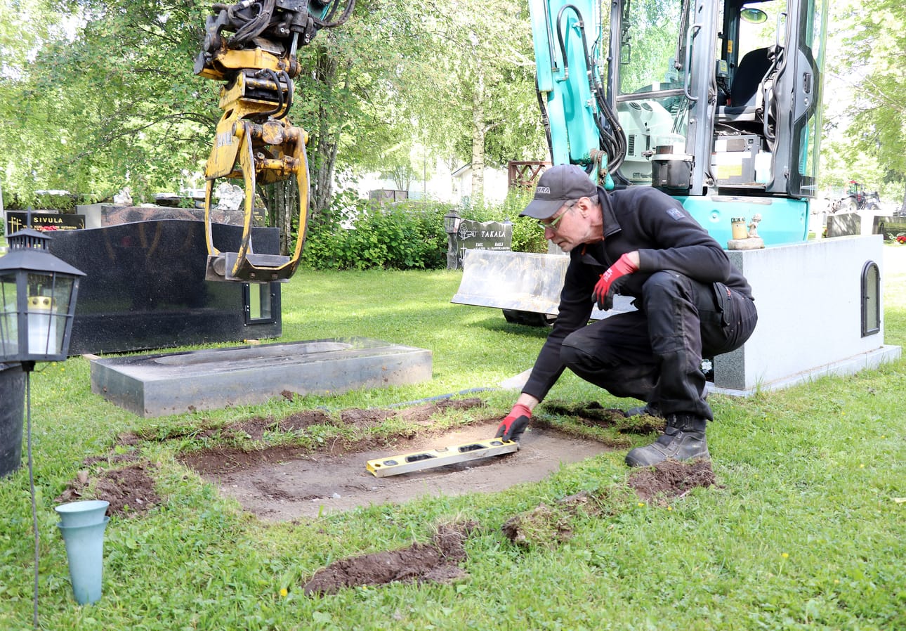 Hautausmaan erityisammattimies Marko Isolehto tekee pohjatyöt tarkasti, jotta hautakivi saadaan suoraan.