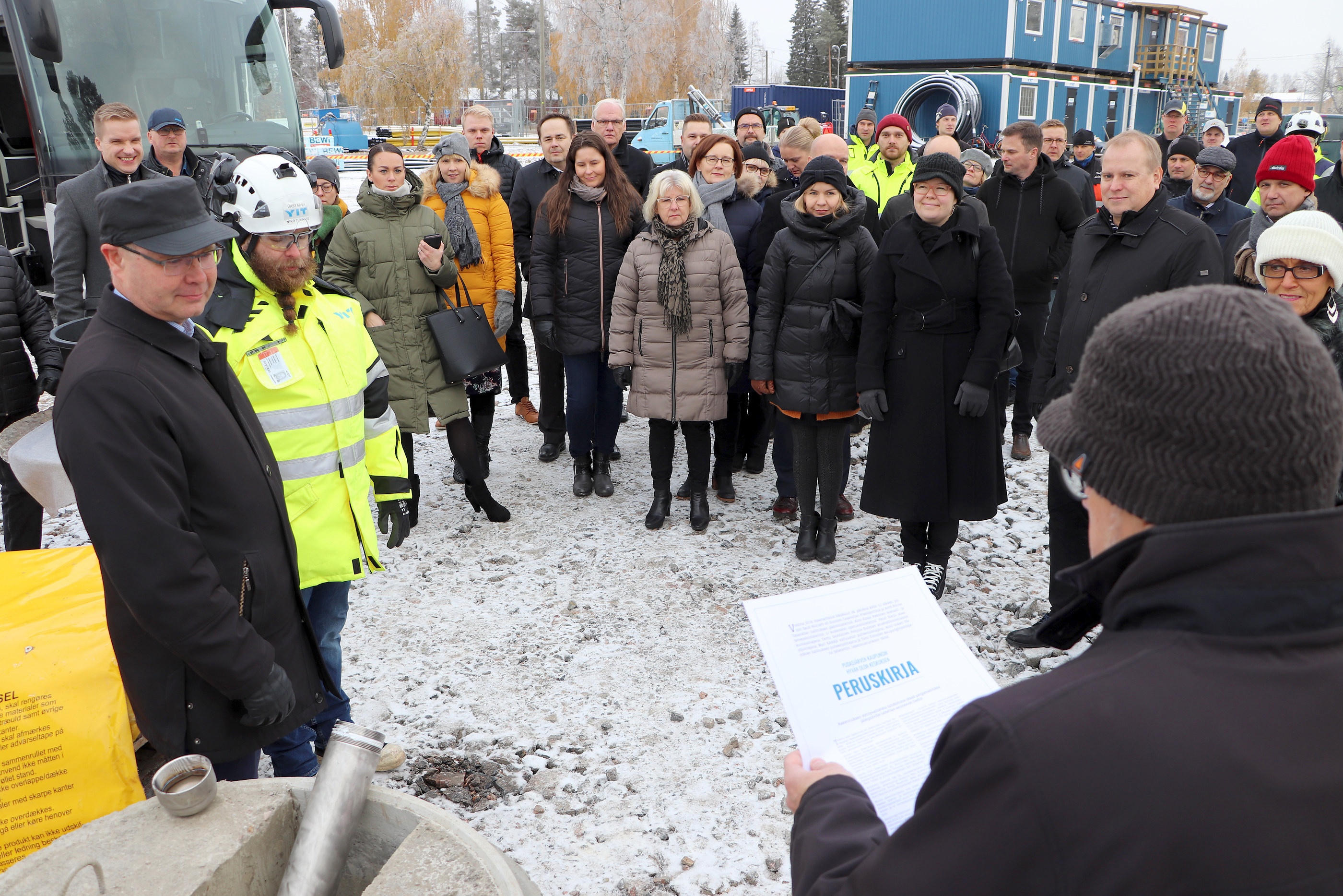 Pääurakoitsija YIT oy:n aluejohtaja Marko Palonen (vas.) ja Hyvän olon keskuksen vastaava työnjohtaja Niko Stenius sekä muu juhlaväki kuuntelivat, kun kaupunginjohtaja Tomi Timonen luki Hyvän olon keskuksen peruskirjaa, joka muurattiin kapselissa rakennuksen peruskiveen. Lisää kuvia verkkopalvelussamme www.iijokiseutu.fi.