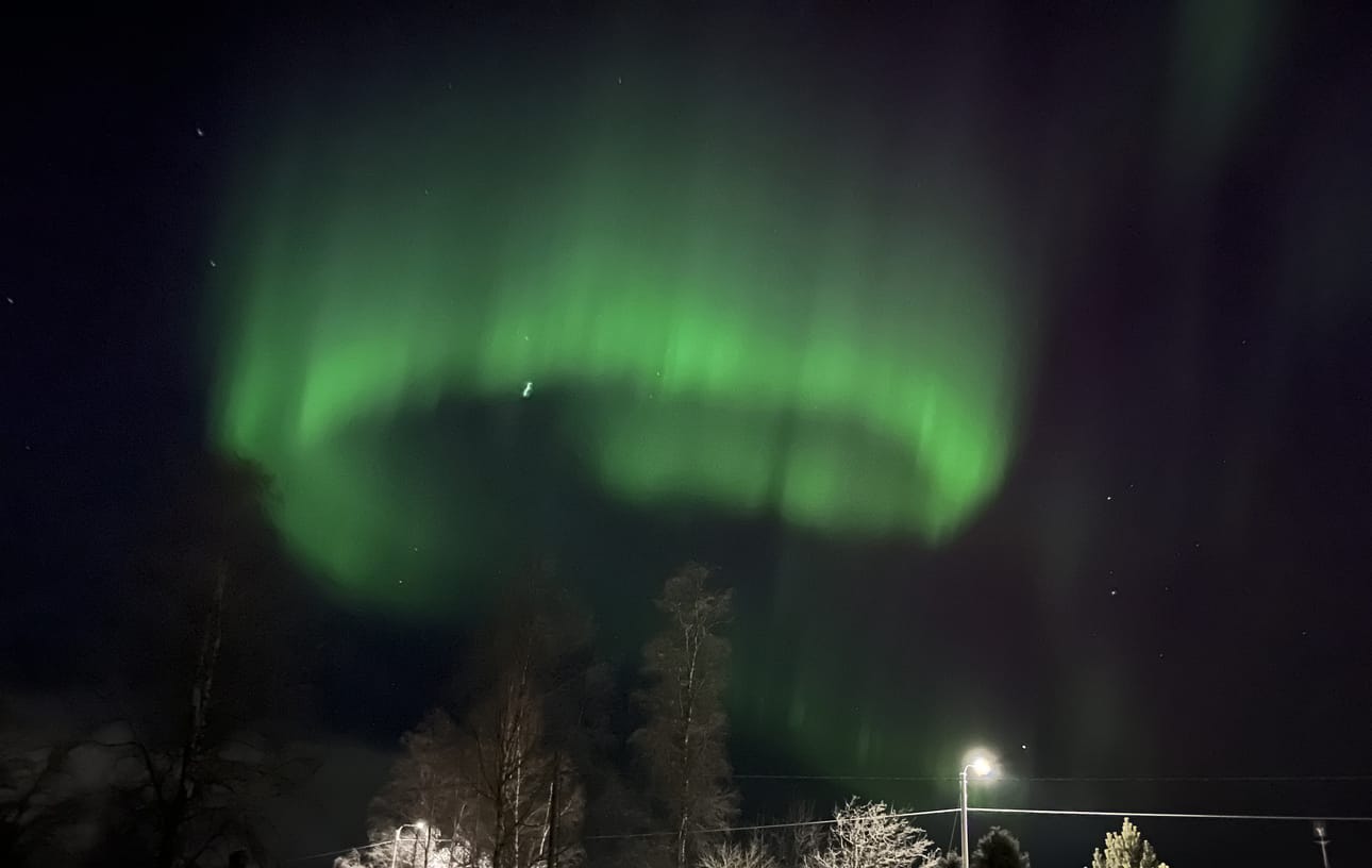 Metsäkylän taivaan yllä näkyi kirkkaita vihreän sävyjä.