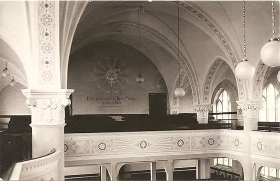 Kauhavan kirkon sisänäkymän on kuvannut Christian Kanderup. Kuva on Museoviraston historiallisesta kuvakokoelmasta. Taustaseinällä näkyy sen ajan maalauksia.