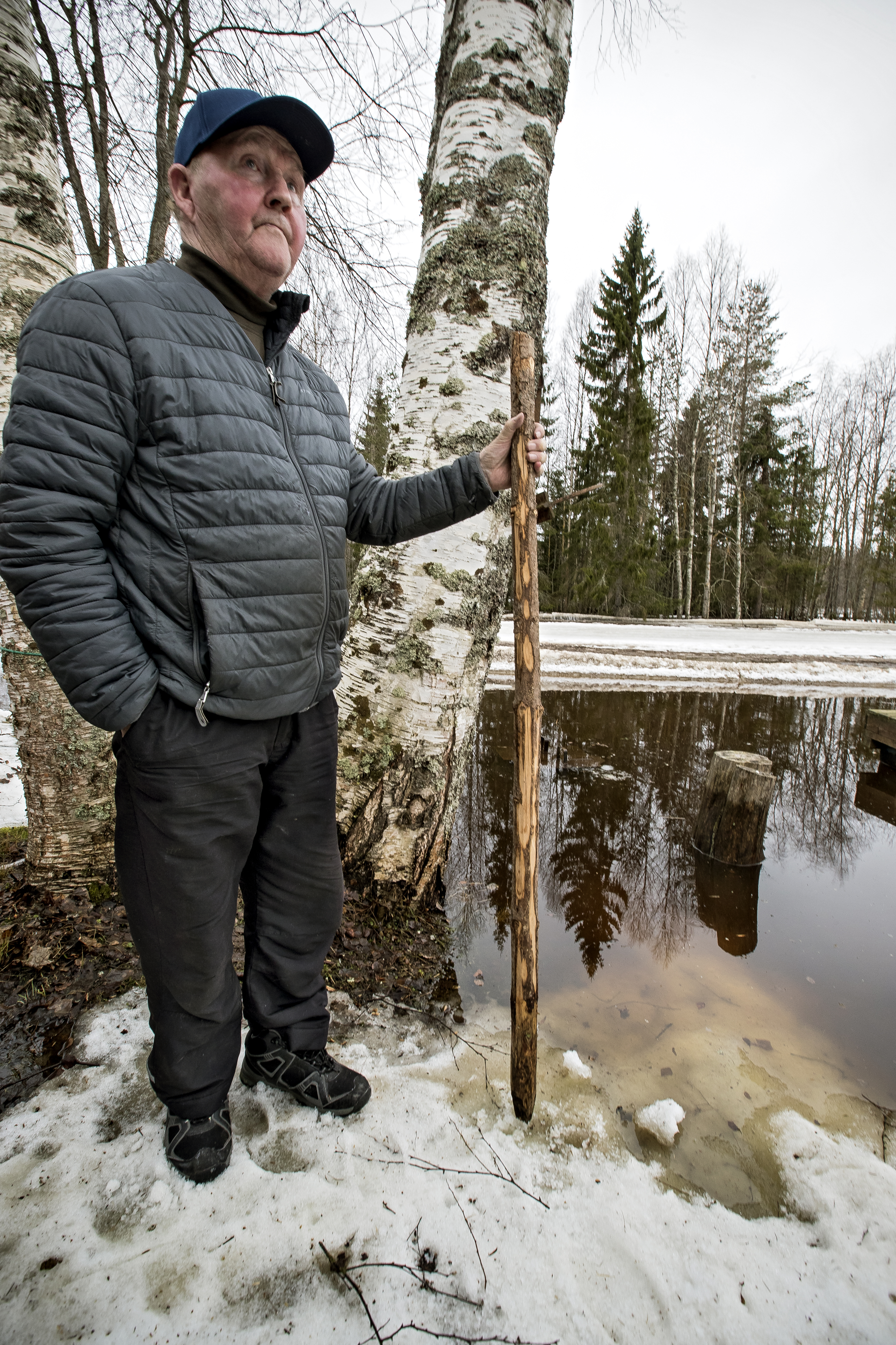 Jorma Halunen mittaa Pirttikosken Kielosaaren kohdalla veden korkeutta ja nostaa kepin aina siihen kohtaa, johon joen vesi on noussut.
