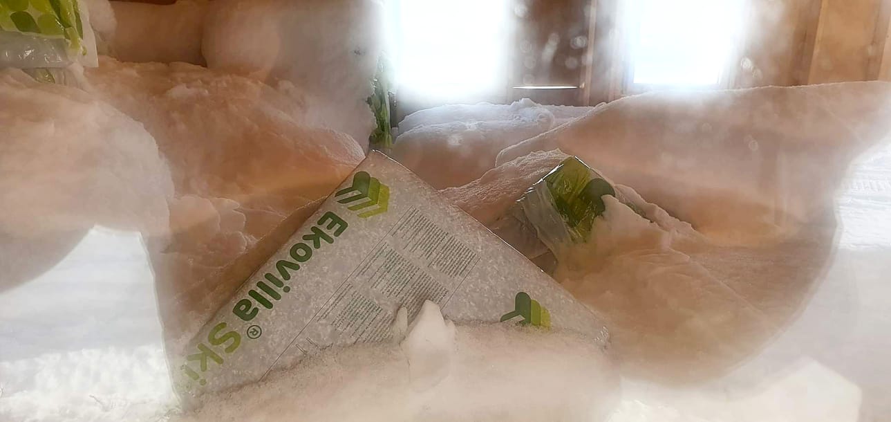 Lumi peittää tuvan sisällä olevia rakennustarvikkeita.