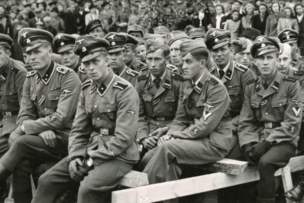 Seinäjoella järjestettiin 14.6.1943 vastaanottojuhla Saksan itärintamalta kotiin palanneille maakunnan pojille. Paikalla oli noin 100 SS-miestä ja 3 000 henkeä yleisöä. Eturivissä vasemmalta Olavi Siltaloppi Ilmajoelta, tuntematon, Vilkas Korpela Kauhavalta ja Juha Veikkola Lapualta. Toinen rivi vasemmalta Antti Mäkinen Alavudelta (näkyy Korpelan ja Veikkolan välistä), Pentti Koivisto Seinäjoelta, Eino Yli-Kankaanpää Lapualta ja Ensio Vuokoski Seinäjoelta. Kolmas rivi vasemmalta: Jouko Ilkka ja Pauli Tiihonen, molemmat Ilmajoelta. Neljäs rivi vasemmalta: Terho Toivonen ja Paavo Maunula, molemmat Lapualta. KUVA: VAASA-LEHDEN VALOKUVAUSOSASTO
