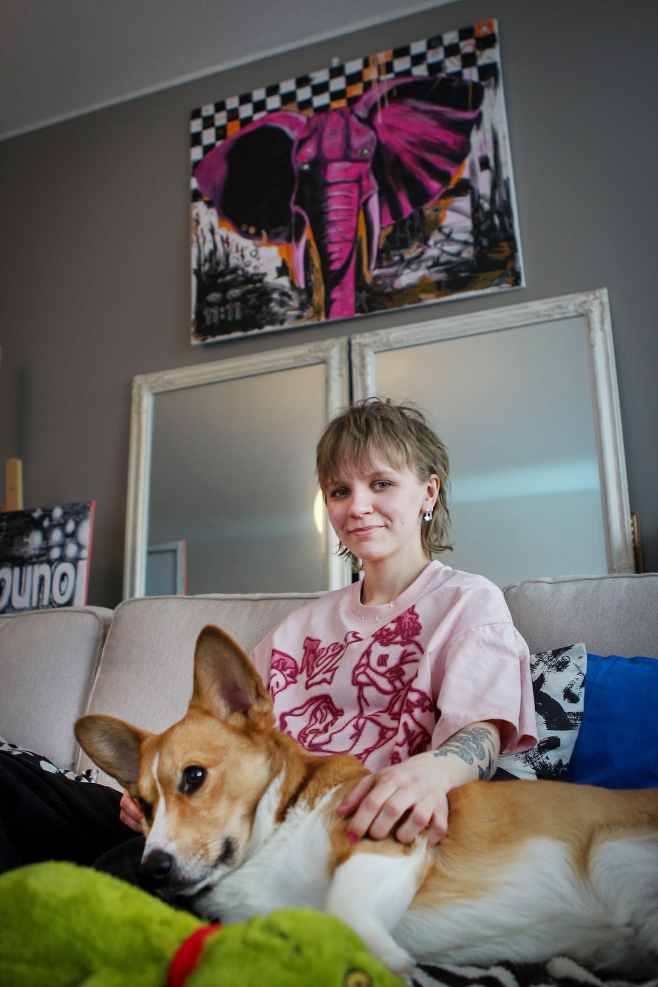 Iida Kangas rapsuttaa kaksivuotiasta Sakke-koiraa kotisohvallaan Torniossa. Peilin ylle on ripustettu Kankaan omaa taidetta.