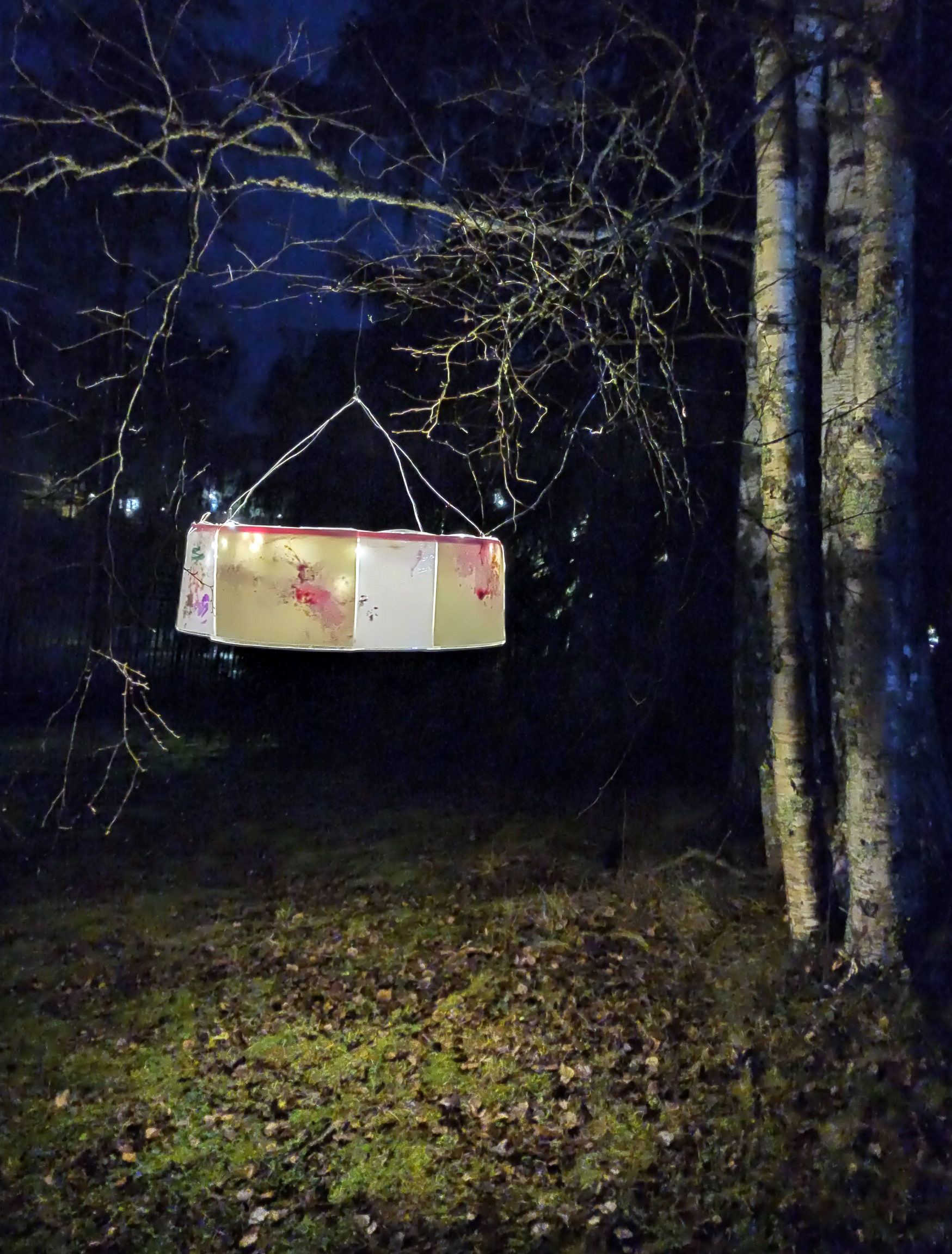 Koivun oksalla riippuvati MLL:n perhekahvilan vauvojen ja taaperoiden väritykset, jotka oli koottu kauniiksi varjostimeksi.