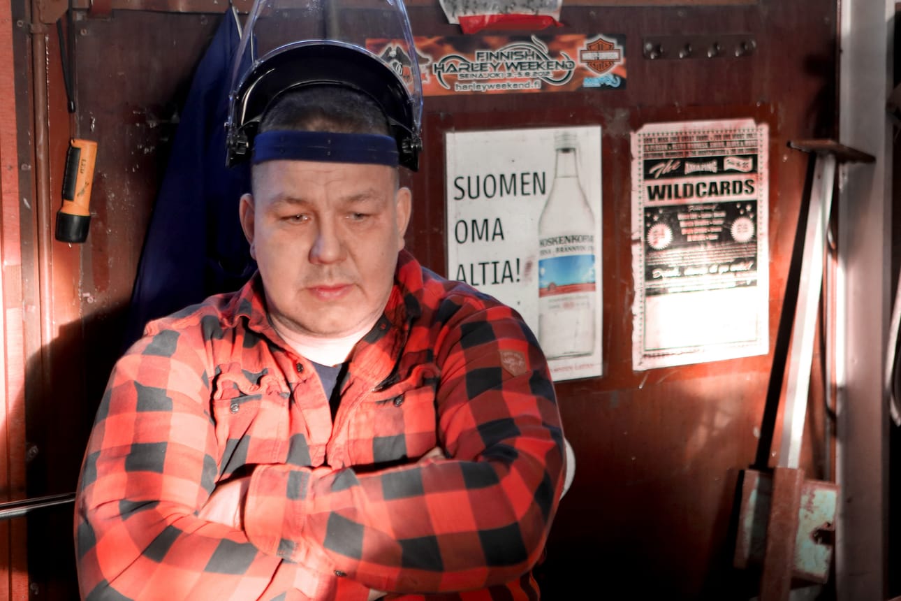 Juha Mäenpää pohtii vielä, mitä kirjoittaa äänestyslapulle. Takana on kylän kuuluisan viinatehtaan mainos.