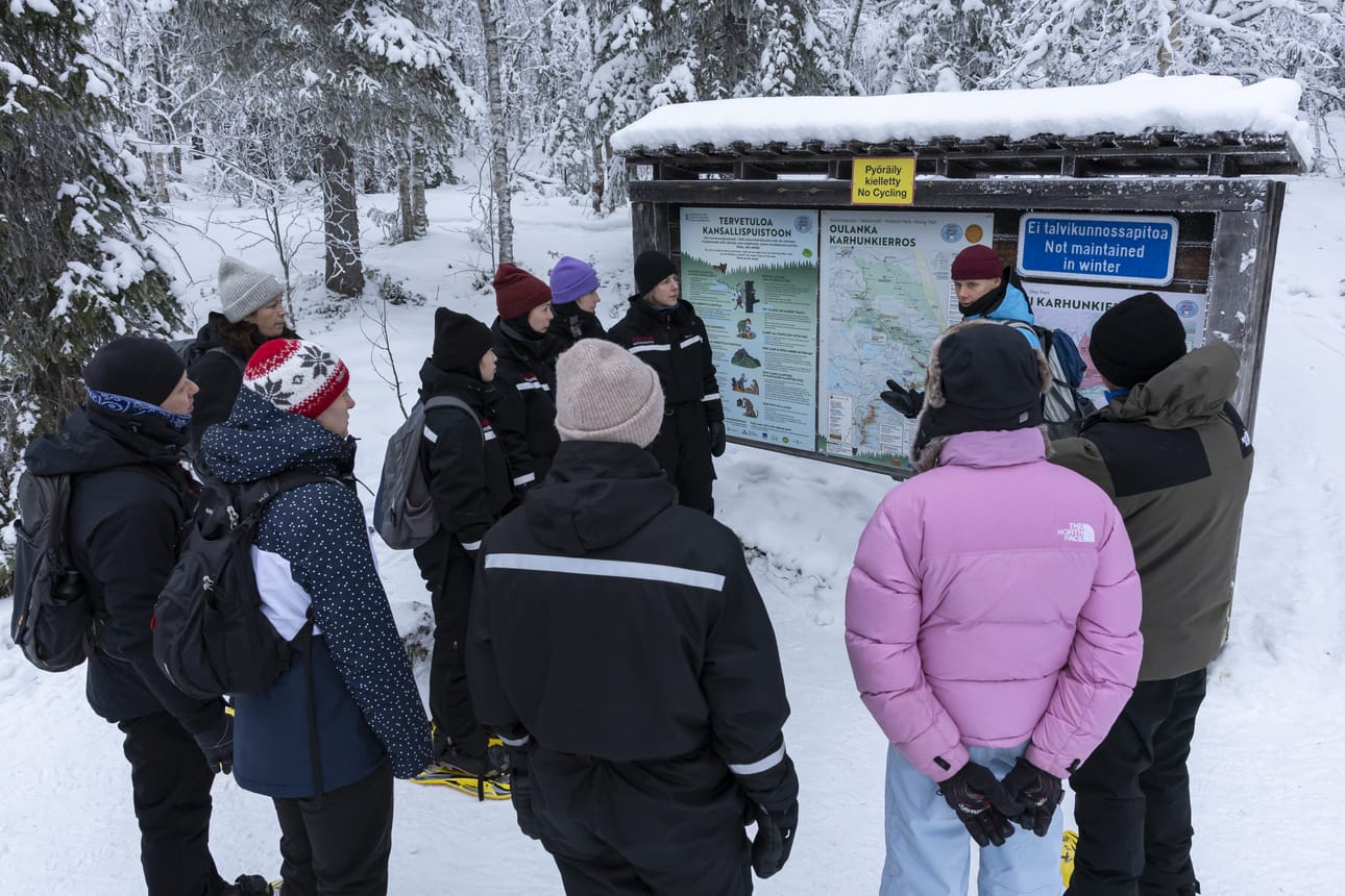 Ruka Adventuresin opas Joona Koskinen näyttää retken alussa kartalta Oulangan kansallispuiston aluetta sekä lumikengin kuljettavaa reittiä.