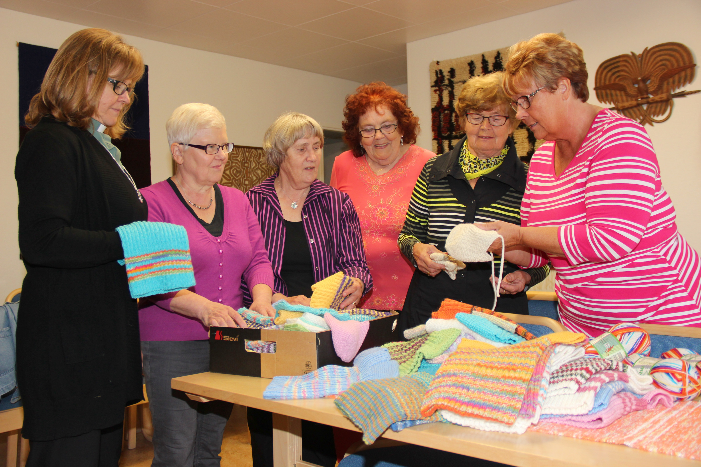 Seurakunnan diakoni Helena Koivukangas koordinoi nuttupiirin toimintaa. Koivukangas ja neulojat, Eeva Mäntykenttä, Sinikka Pietilä, Hilja Honkanen, Silja Ahonen ja Eija Kuosmanen, ihastelevat valmiita nuttuja Kanttorilassa. Viime vuonna Pudasjärveltä maailmalle lähti 170 nuttua ja vuonna 2013 200 nuttua.
