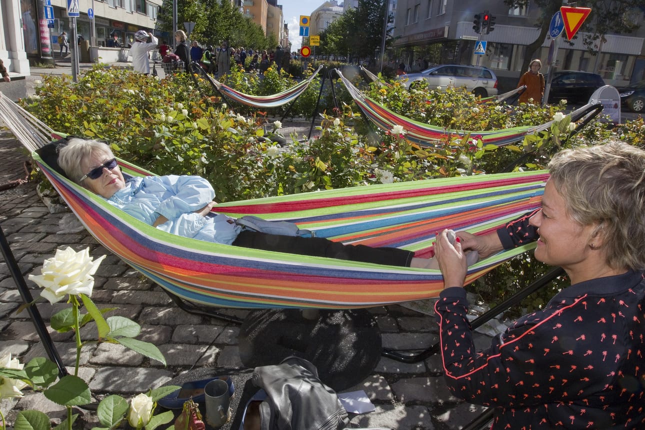 Mirja Seppi rentoutui hetken Pakkahuoneenkadun ruusuteoksen keskelle tuodussa riippumatossa samalla kun taitelija Kaisa Salmi antoi hänelle jalkahieronnan.