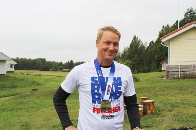 Hymy ei ole hyytynyt Viinikaisen kasvoilta vaikeista ajoista huolimatta. Kaulaa koristaa mitali teräsmies-kilpailusta. KUVAT: TIIA ETELÄMÄKI