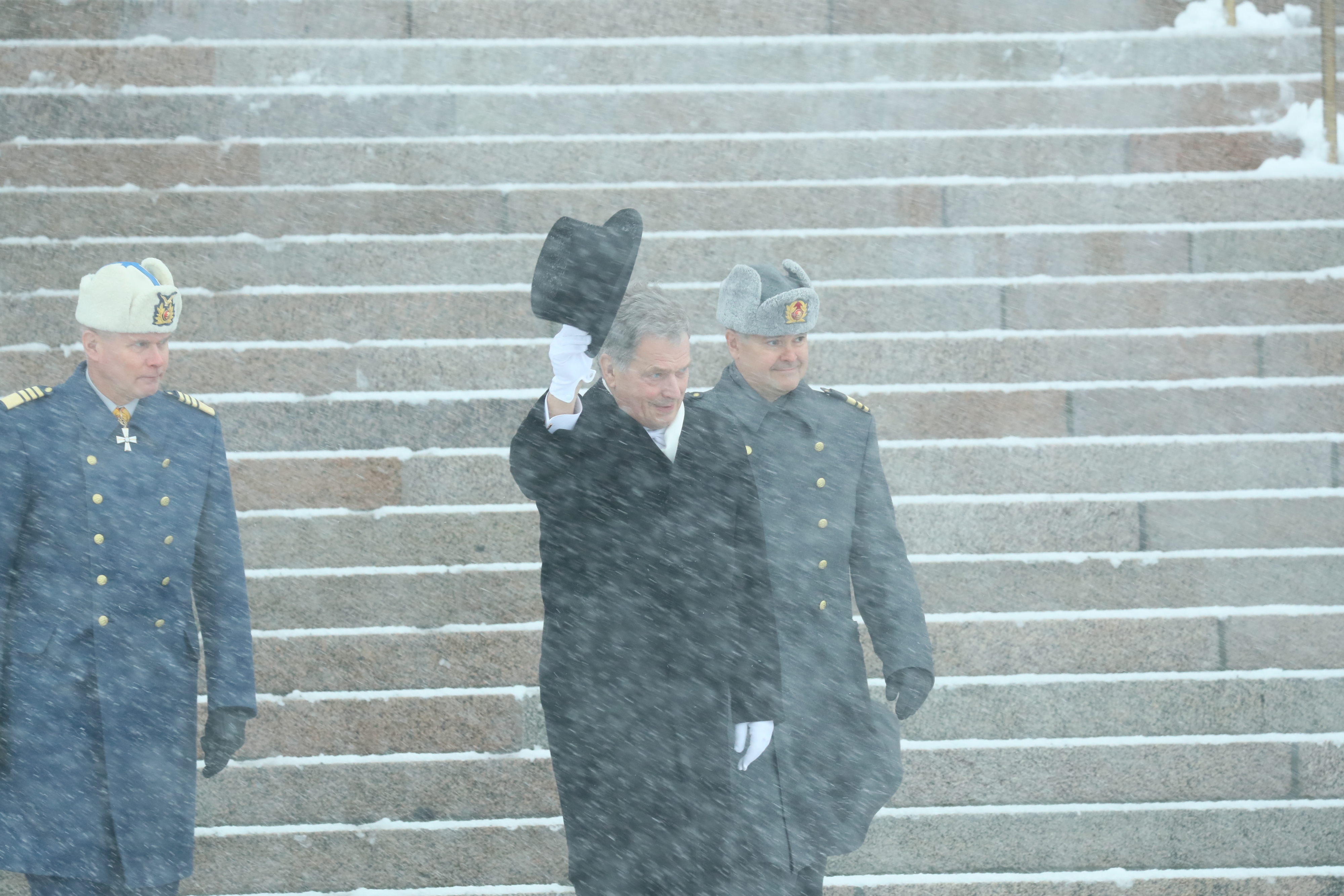 Presidentti Sauli Niinistö tervehti yleisöä ottamalla silinterin päästään Helsingin surkeassa talvisäässä Eduskuntatalolla.