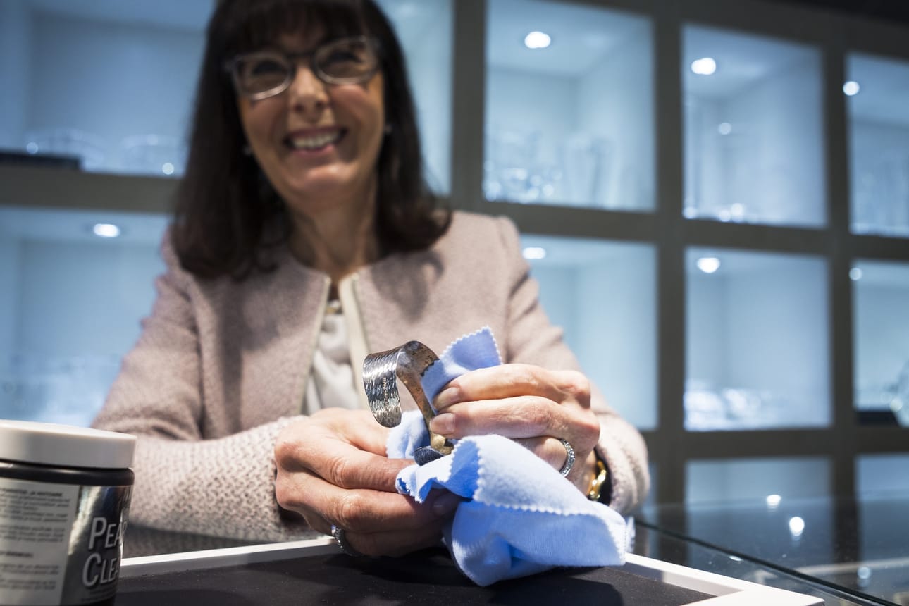 Marja-Leena Salkari kiillottaa rannekorun hopeanpuhdistusliinalla.